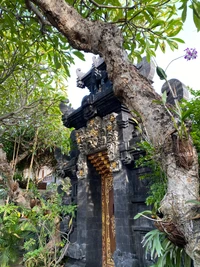 Entrada do templo em Bali cercada por folhagem exuberante e intrincadas esculturas em pedra.