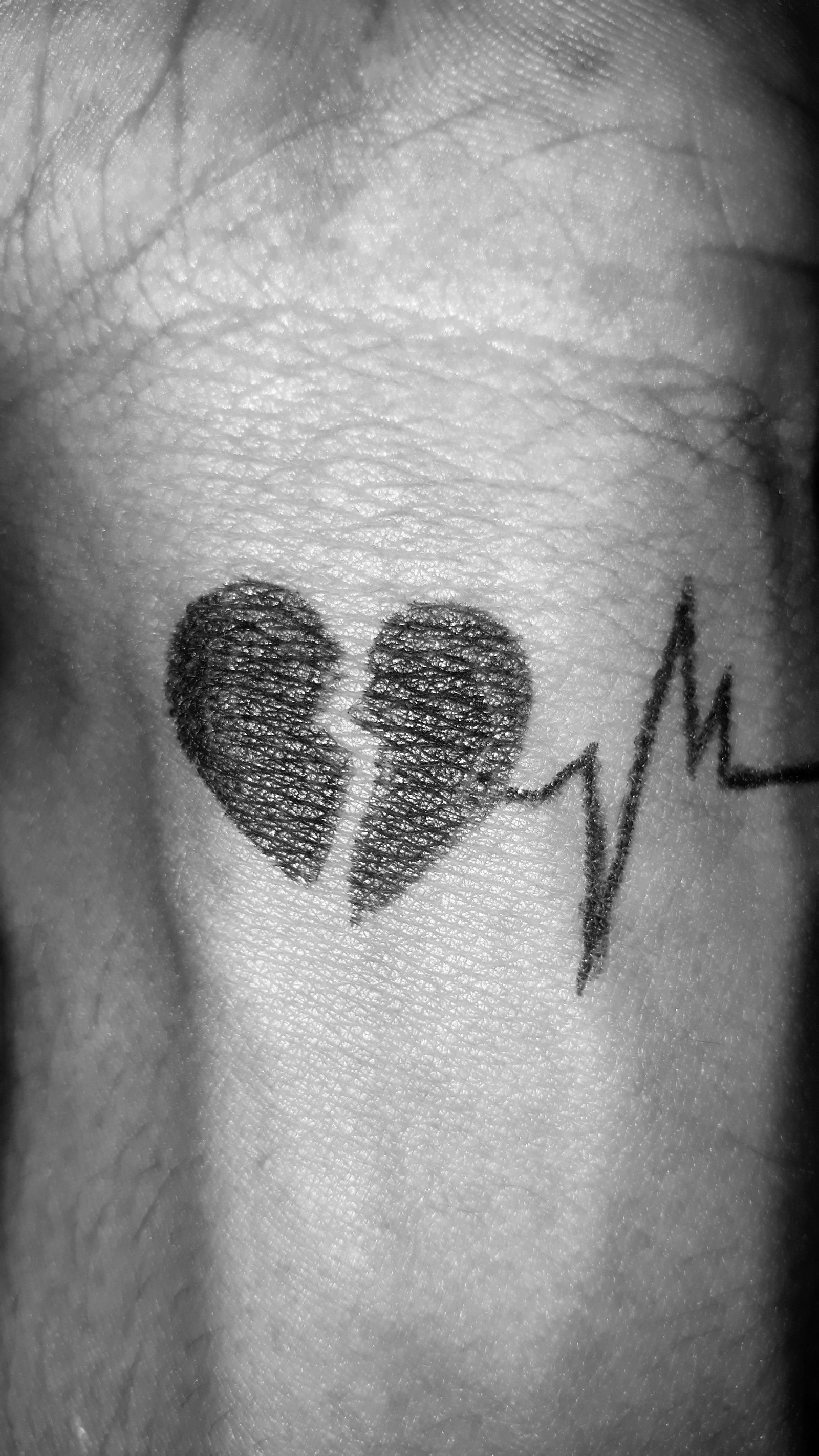 A black and white photo of a man with a tattoo of a heart and heartbeat (love, sad)