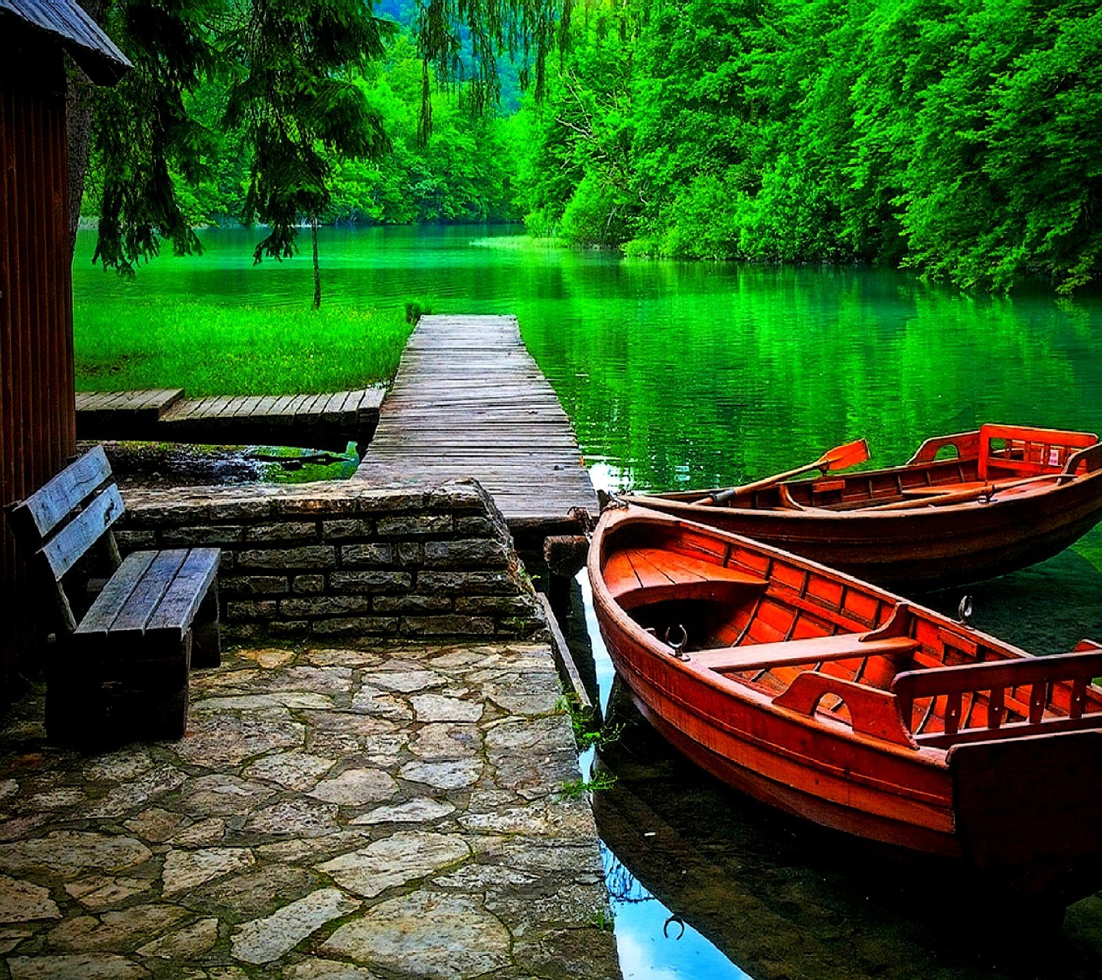 Boats are docked on a dock near a lake with a bench (nature)