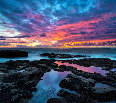 Coucher de soleil vibrant sur la côte rocheuse avec des nuages dramatiques