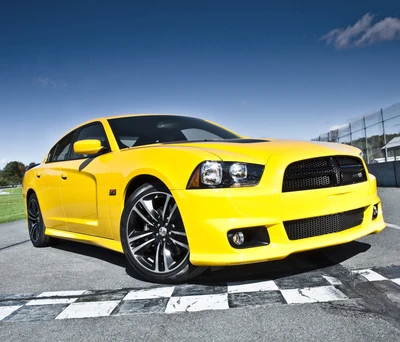 Dodge Charger jaune sur une piste de course avec une ligne d'arrivée à damier.