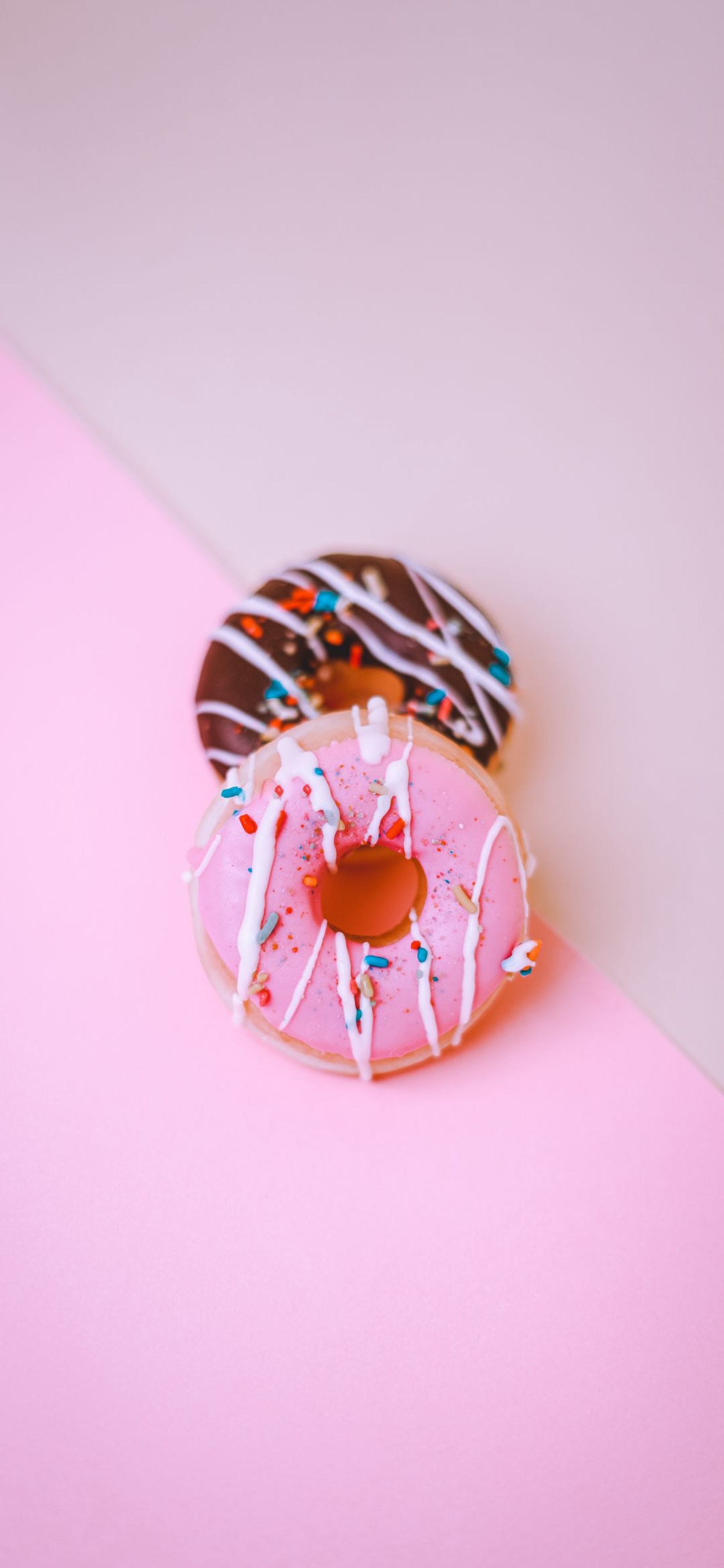 Hay dos donuts que están sentados sobre una superficie rosa (donut, pastelería, pastel, comida, juguete)