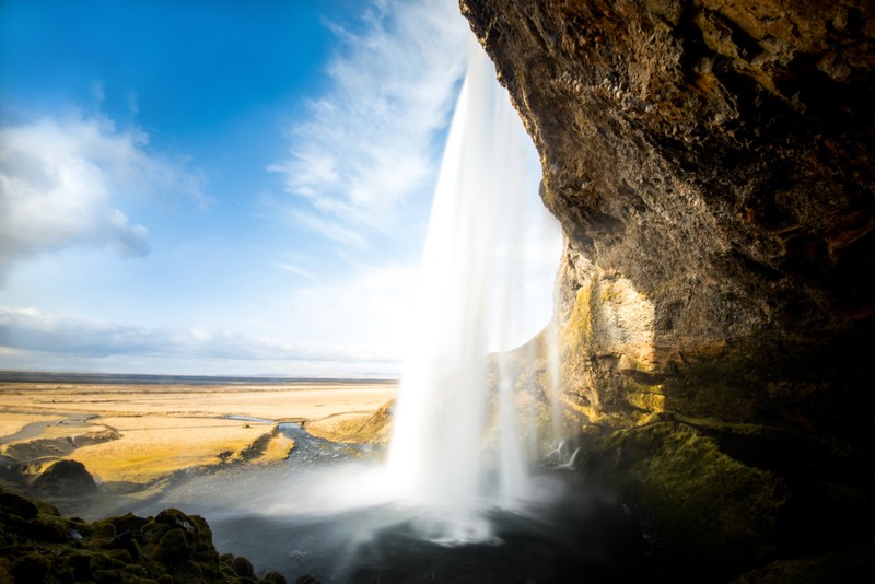 Вид на водопад, вытекающий из пещеры в поле (сельяландсфосс, seljalandsfoss, водопад, природа, вода)