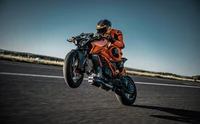 2024 KTM 1390 Супер Дюк Р: Мотоциклист выполняет вилли на гоночной трассе