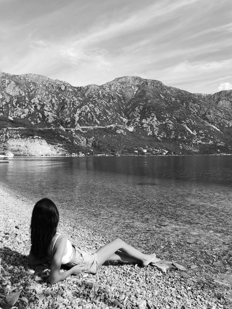 Арабская женщина, сидящая на пляже и смотрящая на воду (вода, горные образования, возвышенность, горный хребет, озеро)