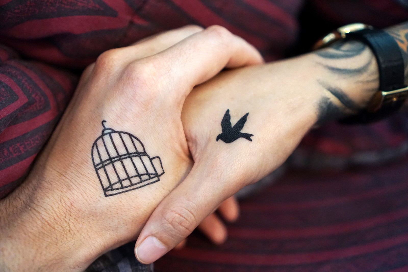 Jemand hat ein tattoo auf seiner hand mit einem vogel und einem käfig (tätowierung, finger, handgelenk, temporäres tattoo, hand)