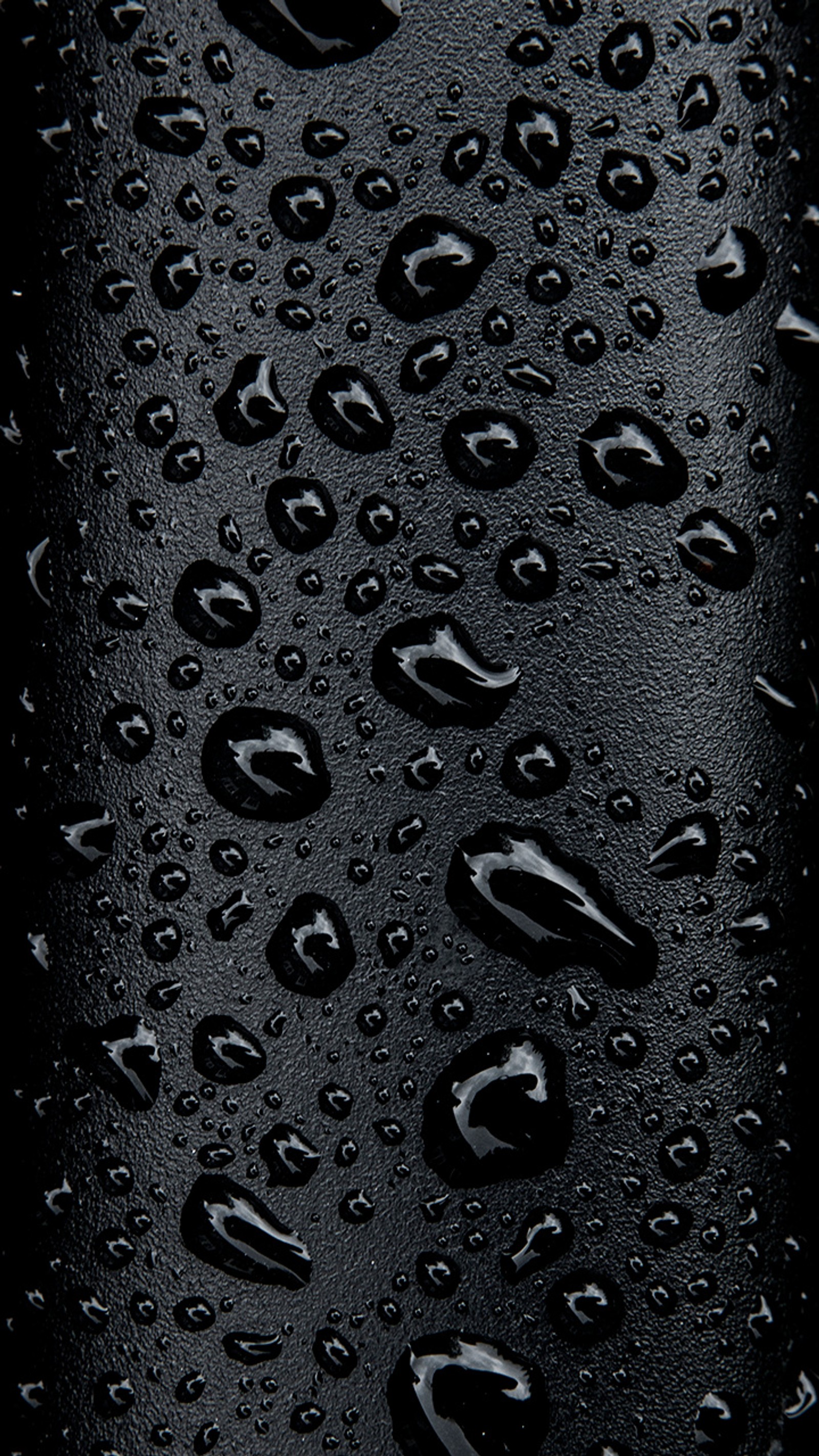 A close up of a black cell phone covered in water droplets (black, dark, droplets, drops, rain)