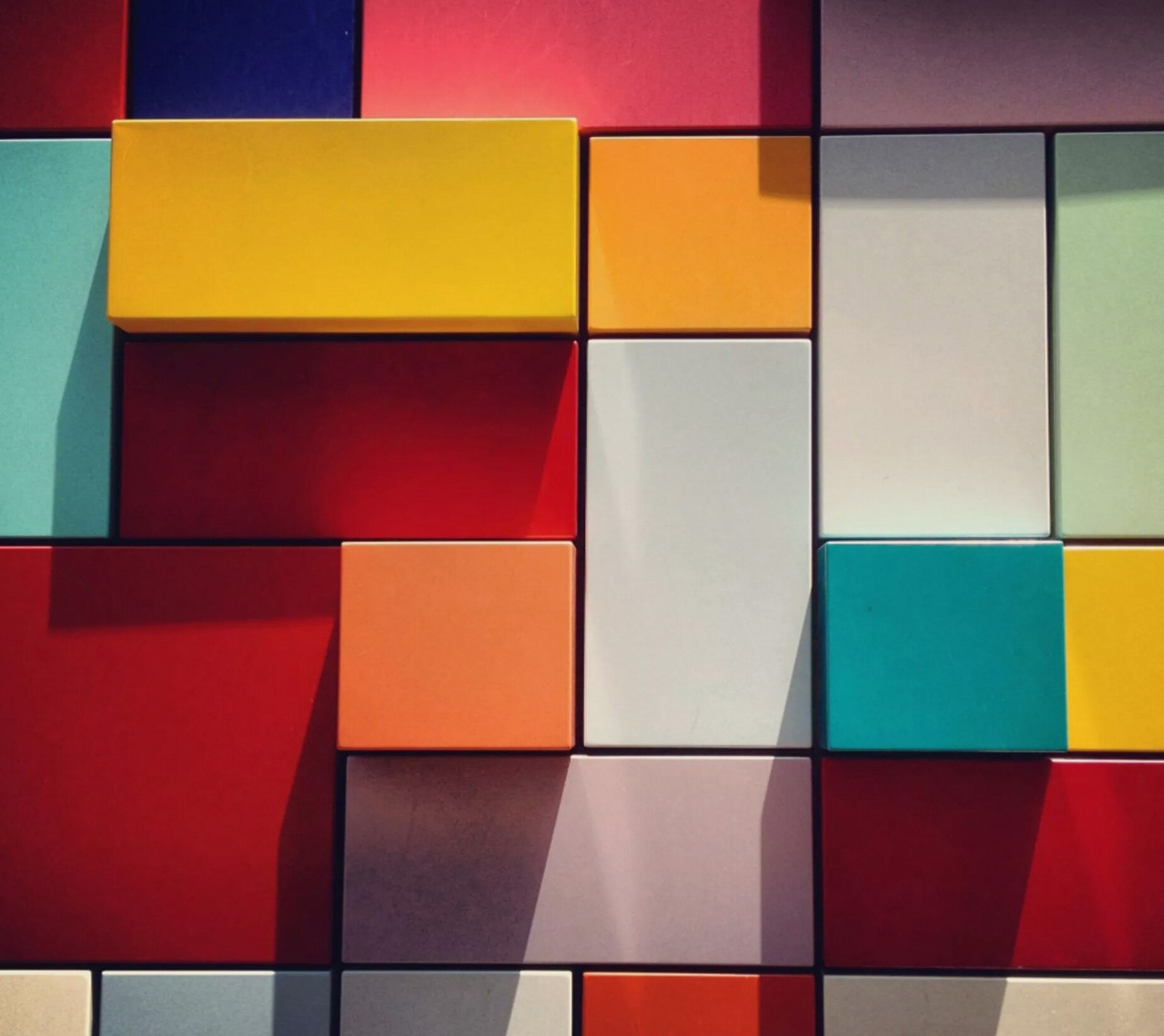 Brightly colored blocks are arranged in a pattern on a wall (abstract, colored, plaid)