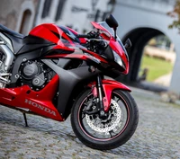 Honda CBR 600RR: Sleek Red Sportbike on Cobblestone Street