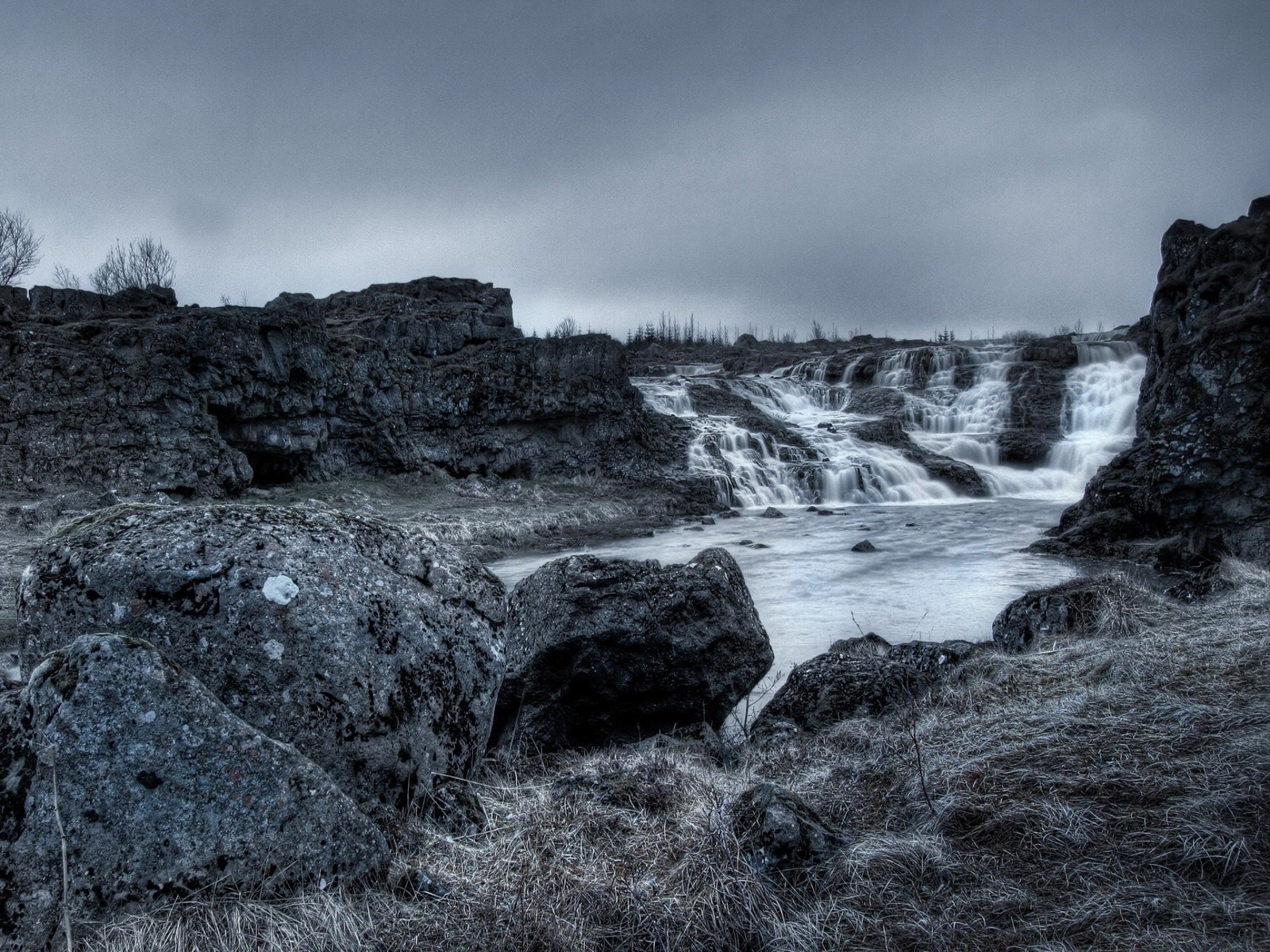 Una cascada en un área rocosa con algunas piedras (blanco y negro, roca, nubes, nube, fotografía monocromática)