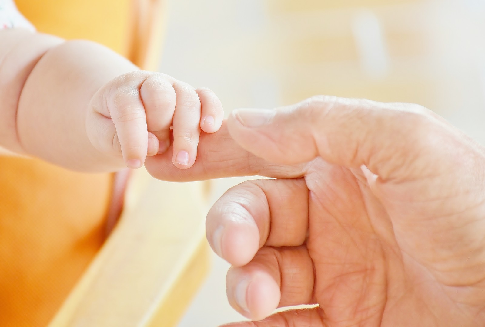 Ein baby, das die hand eines erwachsenen hält (baby hands, säugling, hände haltend, hände zusammen, süßes baby)