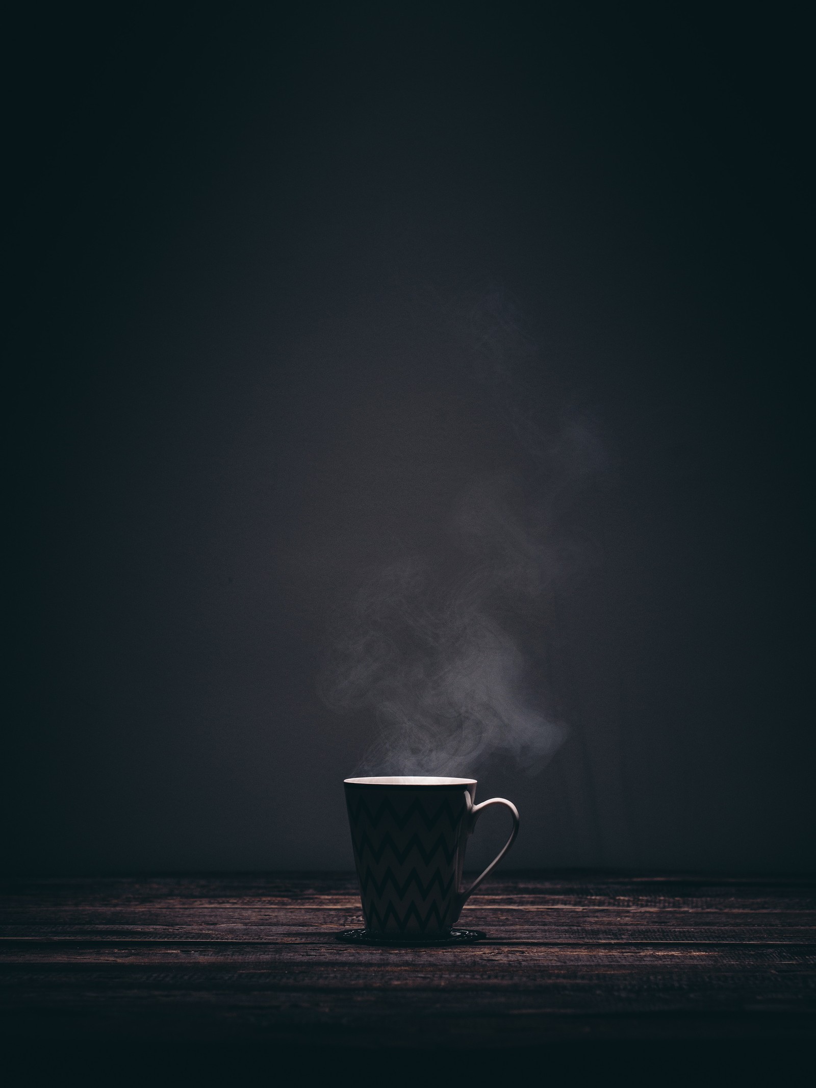 Eine tasse kaffee auf einem holztisch mit aufsteigendem dampf (blau, wolke, atmosphäre, schwarz, schwarz weiß)