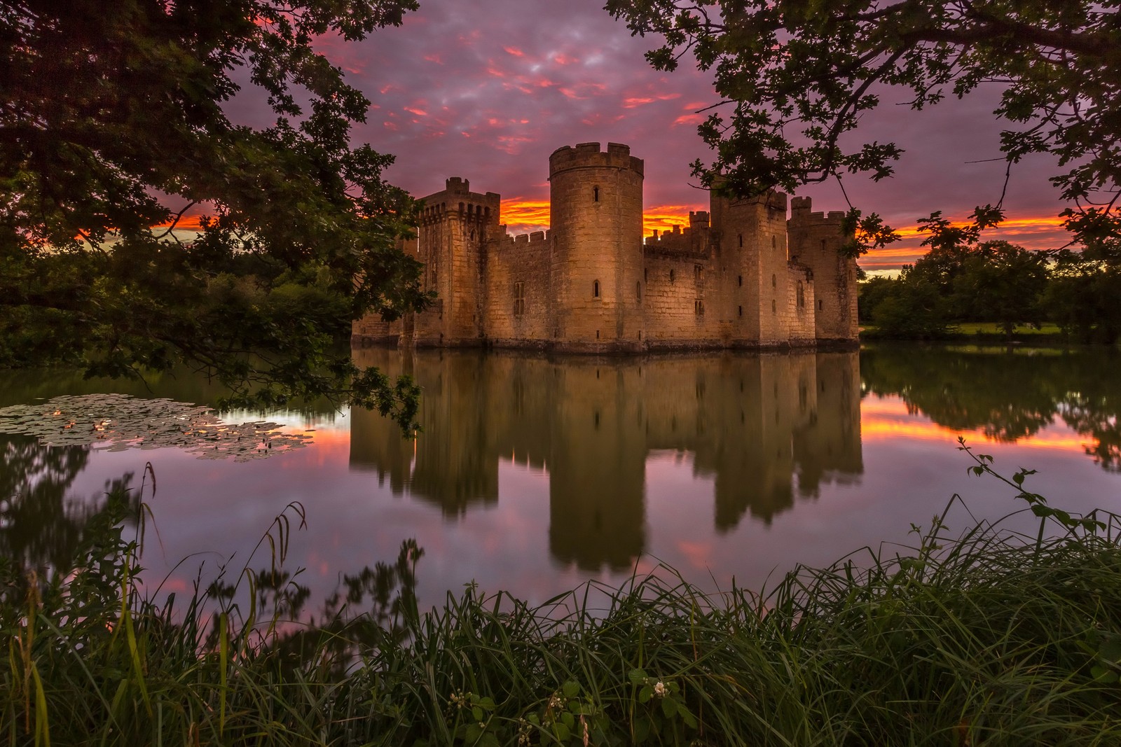 Blick auf ein schloss mit einem wassergraben und einem sonnenuntergang im hintergrund (burg, sonnenuntergang, reflexion, natur, natürliche landschaft)