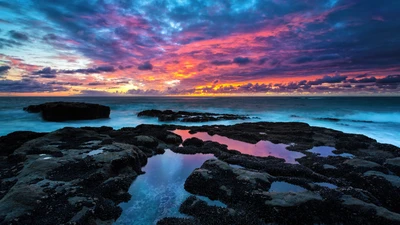 Coucher de soleil vibrant sur la côte rocheuse avec des bassins de marée réfléchissants