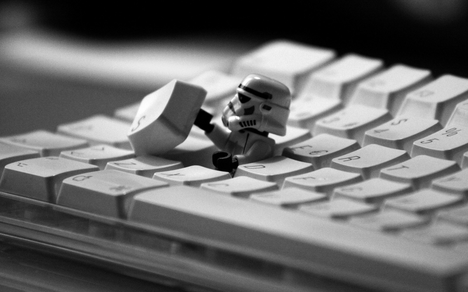 There is a toy that is sitting on a keyboard with a storm trooper (close up, monochrome photography, keyboard, monochrome mode, computer keyboard)