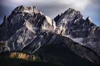 Majestuosos Dolomitas: Picos Cubiertos de Nieve y Vegetación Verde en la Luz del Día.