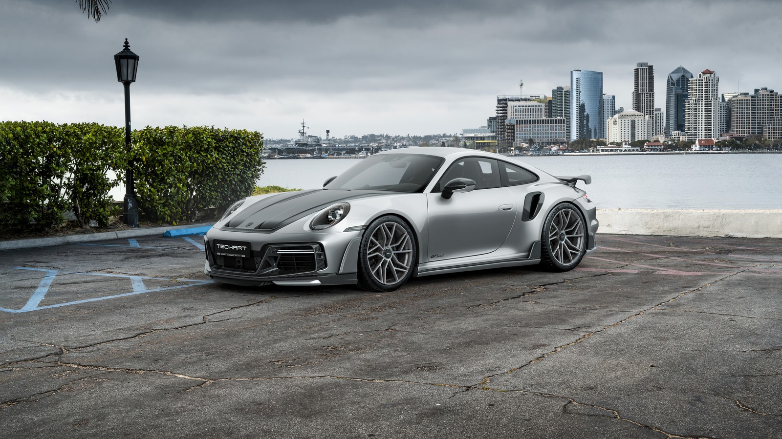 Un porsche gts plateado estacionado en un aparcamiento con una ciudad de fondo (porsche 911 turbo s, techart gtsport, 5k, coches, fondo de pantalla 4k)