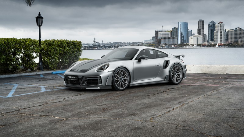 Серебристый porsche gts, припаркованный на парковке на фоне города (porsche 911 turbo s, techart gtsport, 5k, машины, обои 4k)