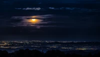 Paisagem urbana iluminada pela lua sob um céu dramático