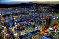 Seoul's vibrant skyline illuminated at night, showcasing a bustling metropolis with a blend of modern skyscrapers and traditional architecture against a mountainous backdrop.