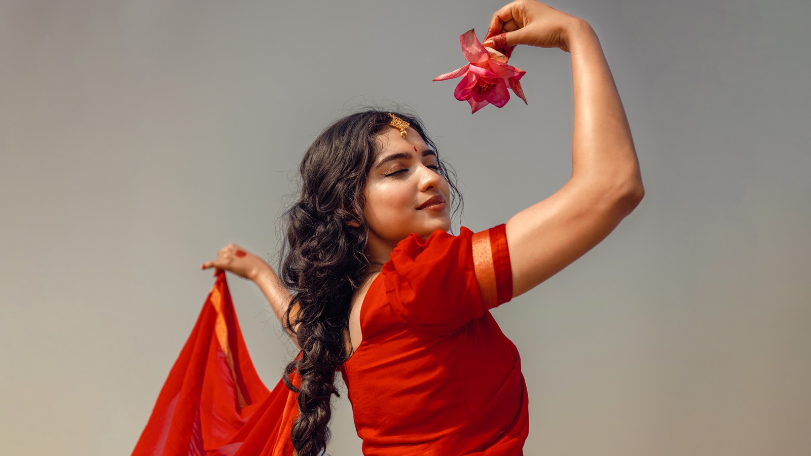 Une femme en robe rouge tenant une fleur dans sa main (mamitha baiju, actrice indienne, séance photo, 5k, 8k)