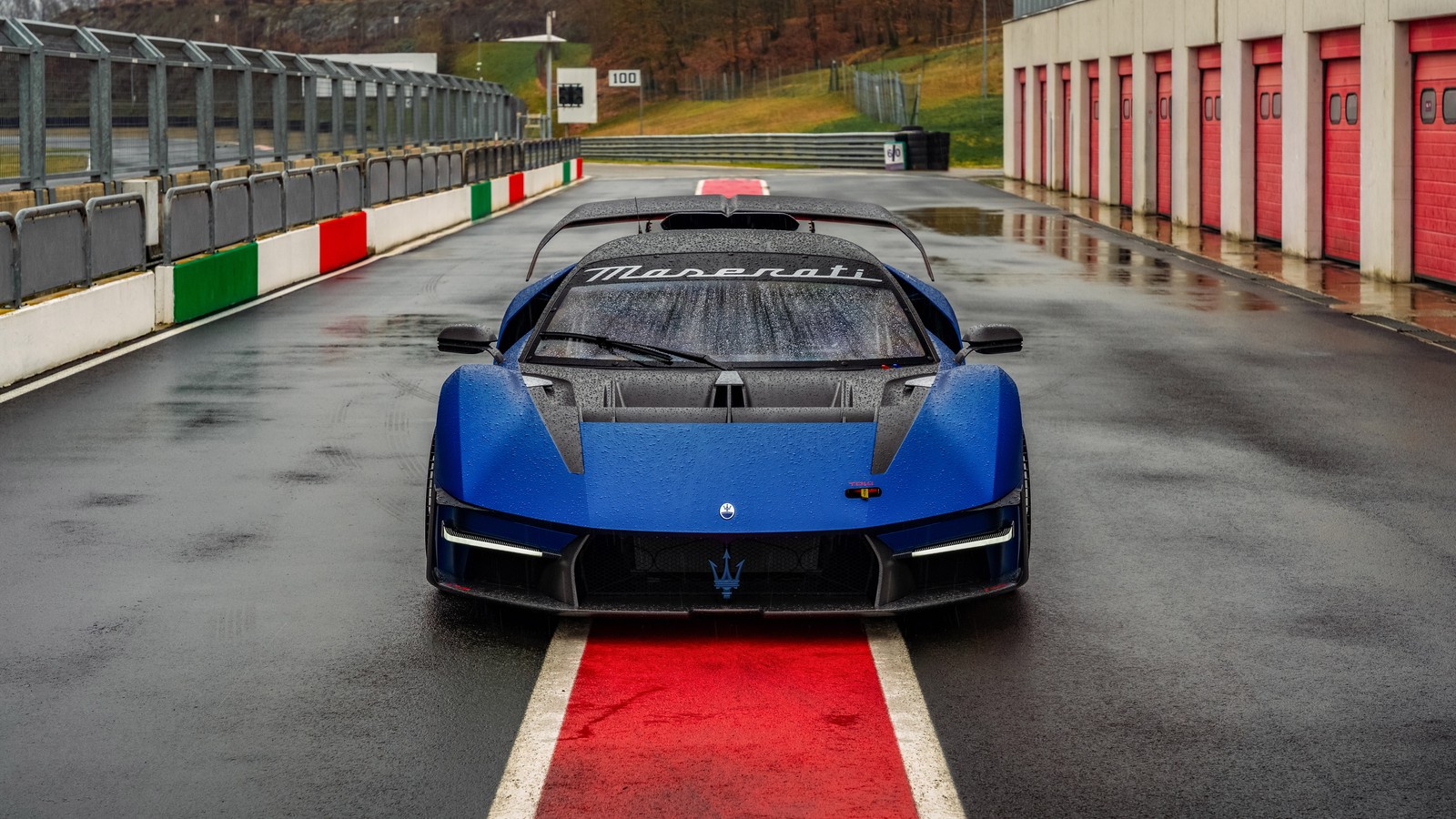 Arafed blue sports car driving on a wet road with red and white stripes (maserati mcxtrema, 8k, 5k, race track, track cars)