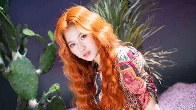 Sana von TWICE strahlt Charme mit lebhaftem orangefarbenem Haar aus und zeigt ihren einzigartigen Stil vor einer tropischen Kulisse.