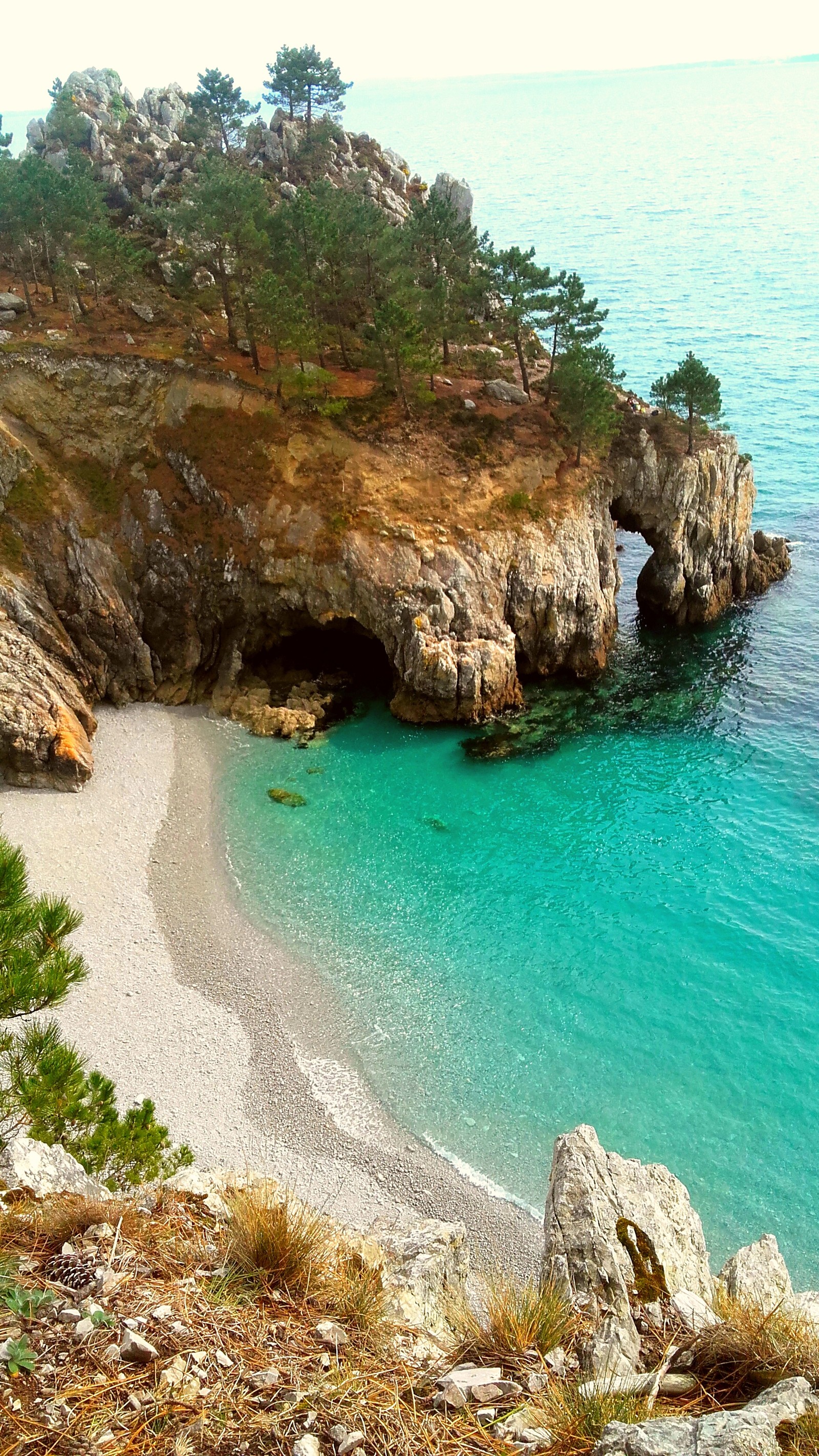 Há uma pequena praia com uma caverna no meio (bretagne, frança, natureza, oceano, praia)