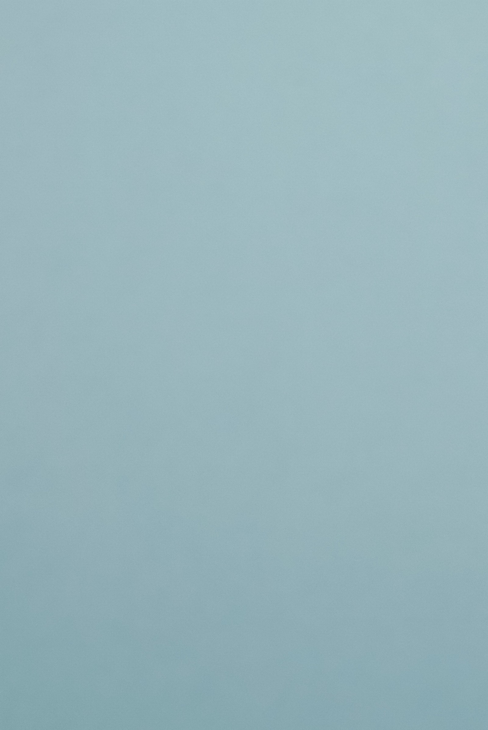 Un hombre volando un papalote en una playa cerca del océano (azul, color, gris, fondo liso)