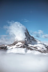 Majestätischer Berggipfel umgeben von Wolken und Schnee