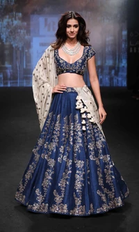 Disha in a stunning blue lehenga with intricate floral embroidery, showcasing elegance on the runway.