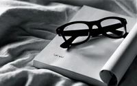 Lunettes reposant sur un livre ouvert en monochrome