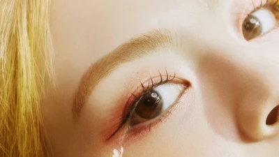 Close-up of a girl group's member showcasing expressive eyes and soft makeup, embodying a dreamy aesthetic.