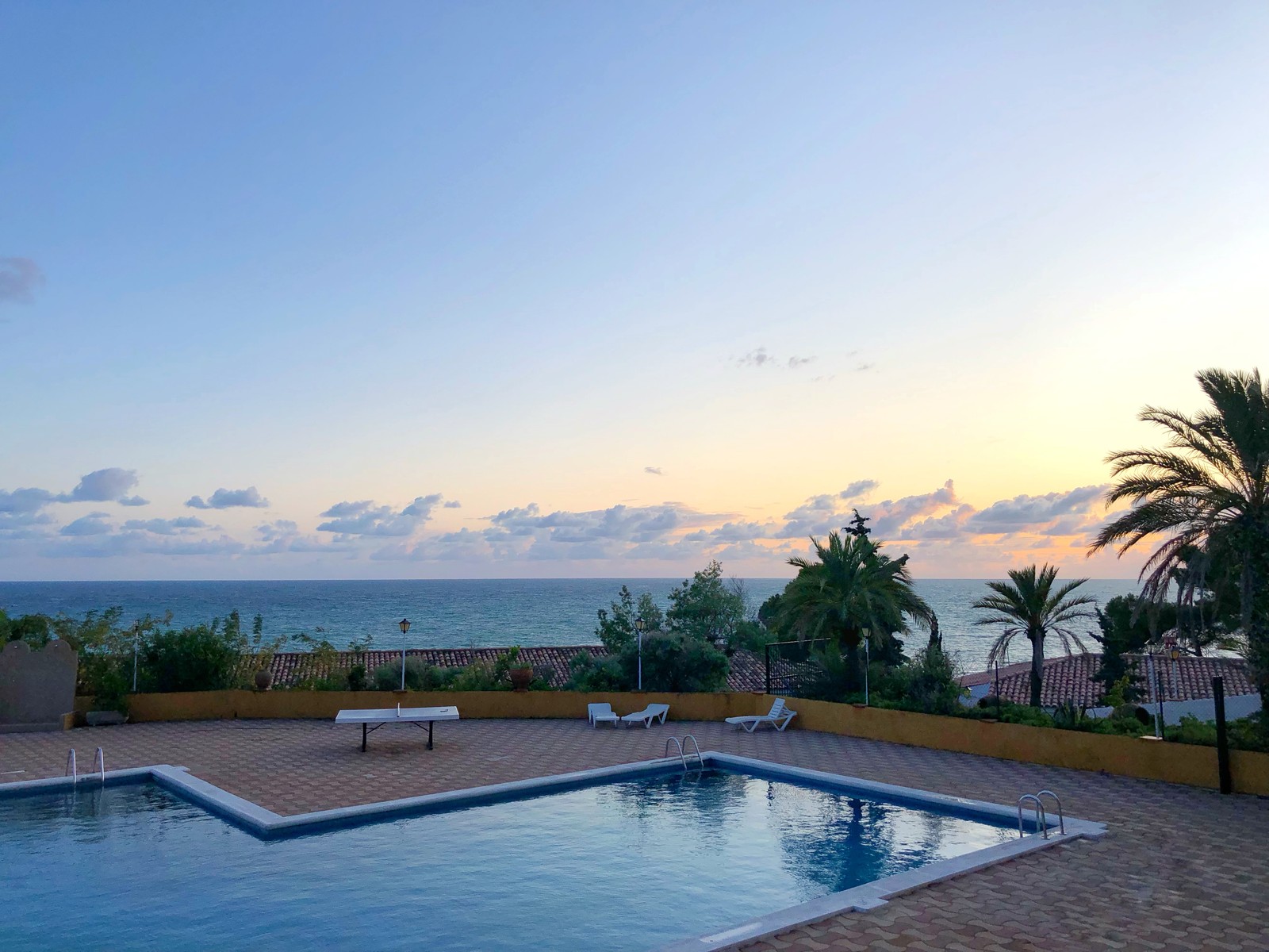 Uma vista de uma piscina com vista para o oceano (estância, piscina, imóveis, palmeiras, propriedade)