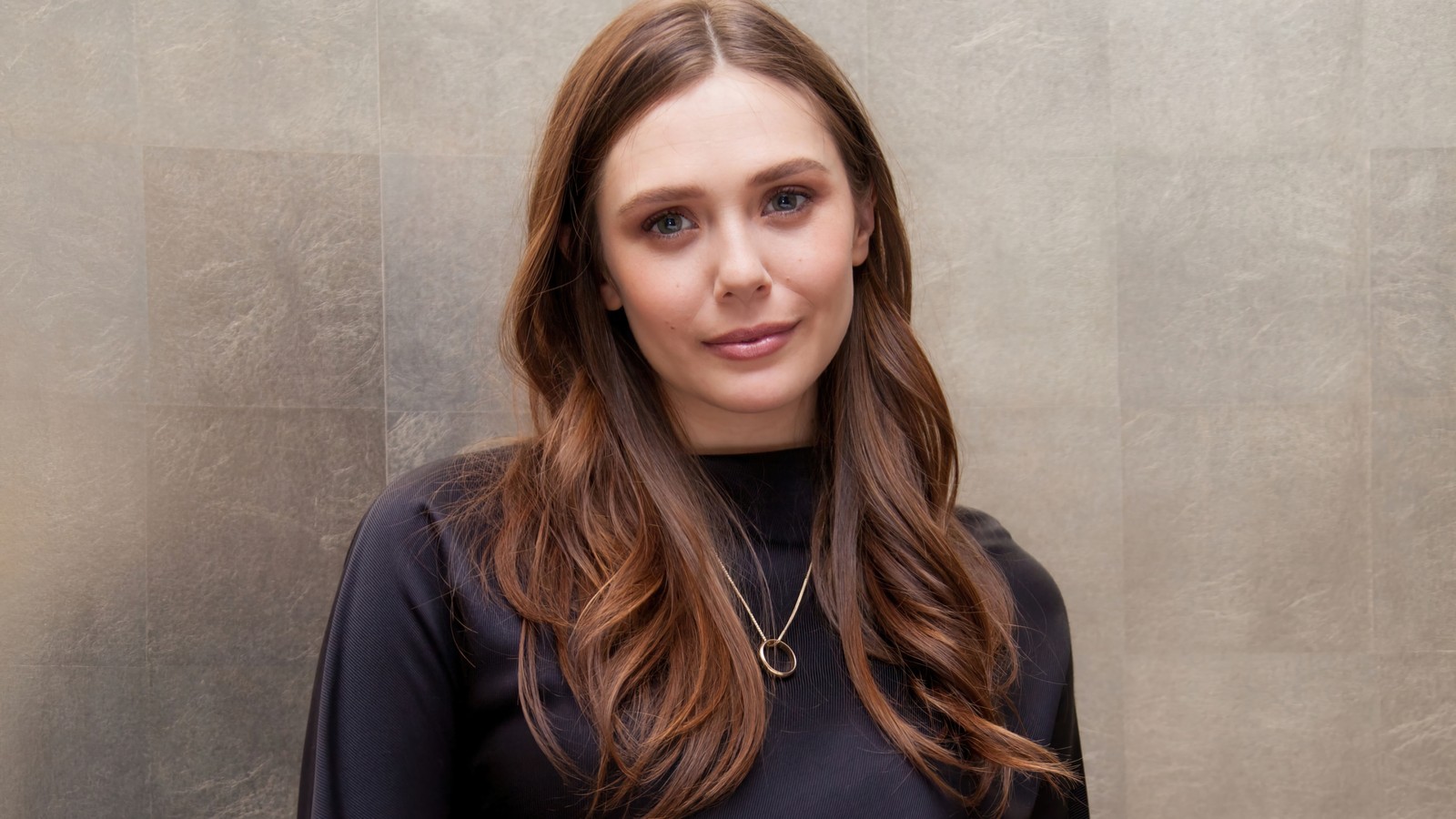 Femme arabe avec de longs cheveux et un haut noir se tenant devant un mur (elizabeth olsen, américain, actrice, célébrité, femmes)