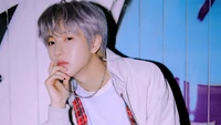 Huang Renjun von NCT Dream posiert nachdenklich vor einem bunten Hintergrund und zeigt seinen stylischen Look aus dem Album "Deja Vu Resonance Pt 1".