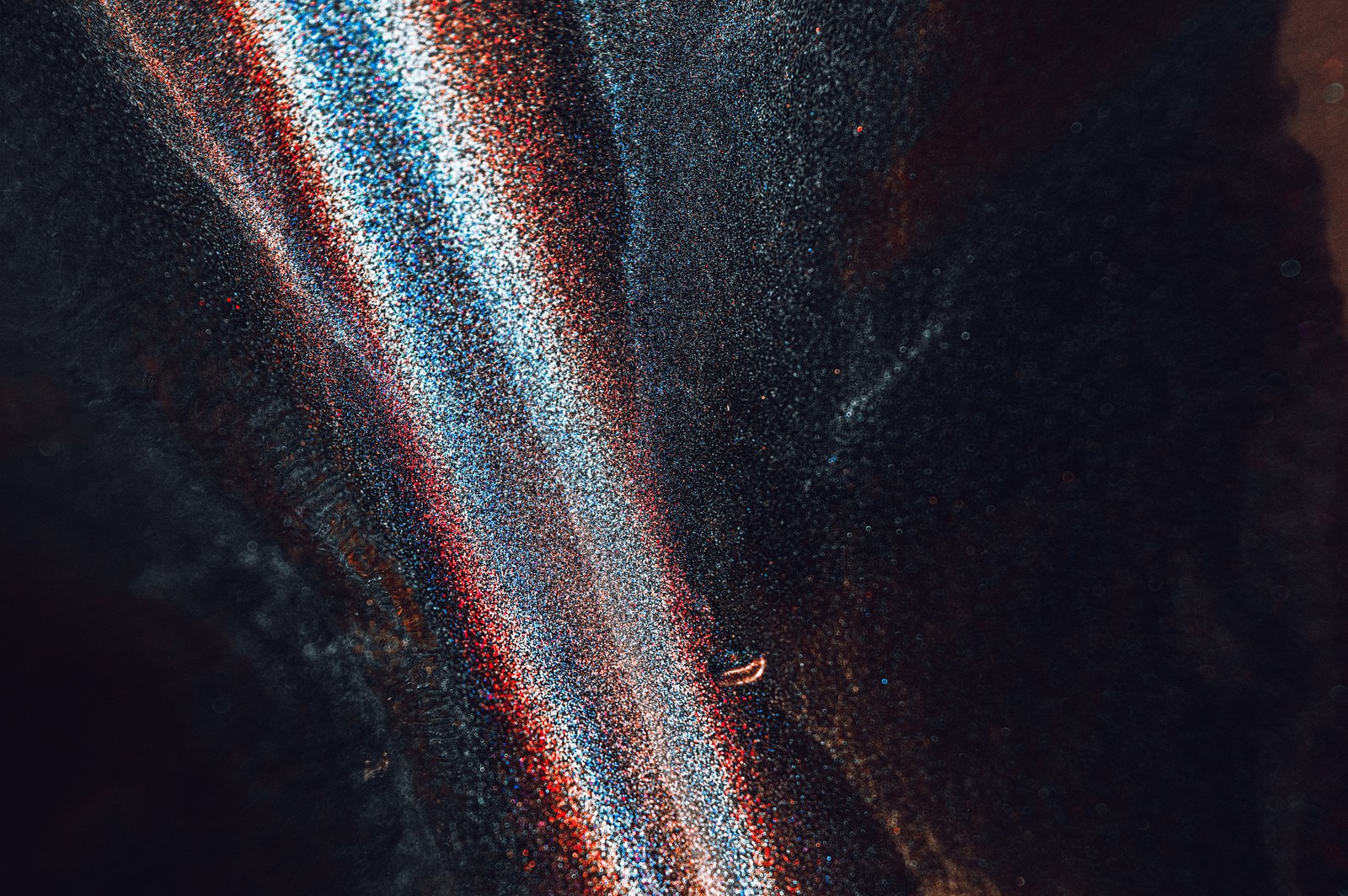 A close up of a black and red striped cloth with a small white object (black, blue, light, brown, pattern)