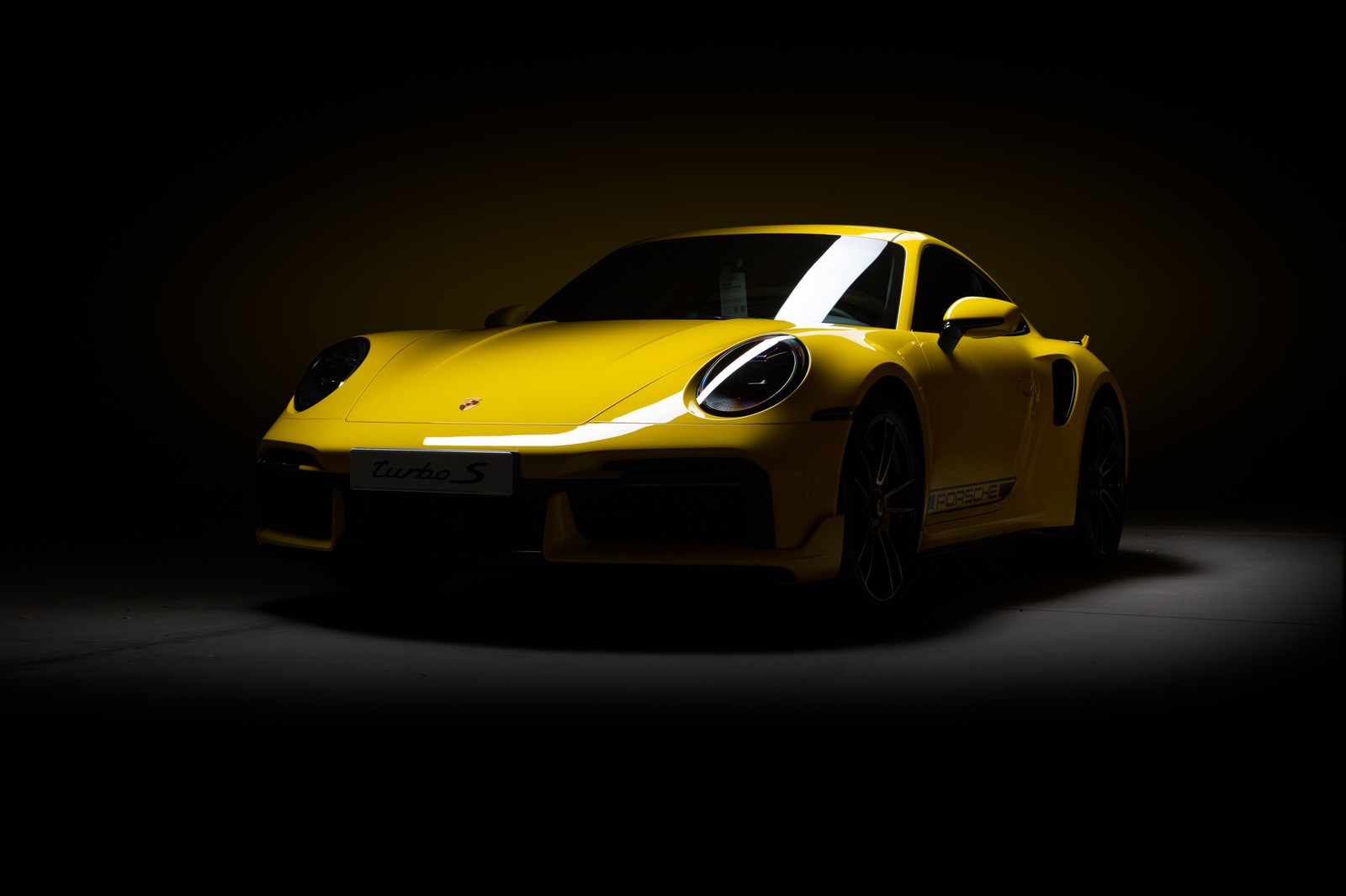 Un primer plano de un coche deportivo amarillo en una habitación oscura (porsche 911 turbo s, cgi, fondo oscuro, coches, fondo de pantalla 4k)