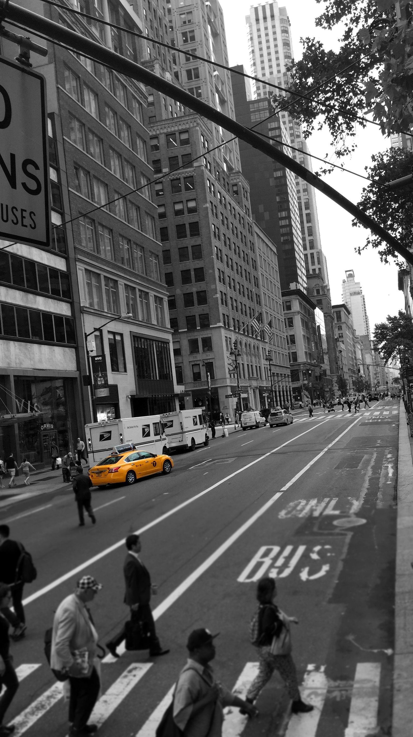 Pedestrians crossing a busy city street in a black and white photo (america, colour bleed, manhattan, new york, taxi)