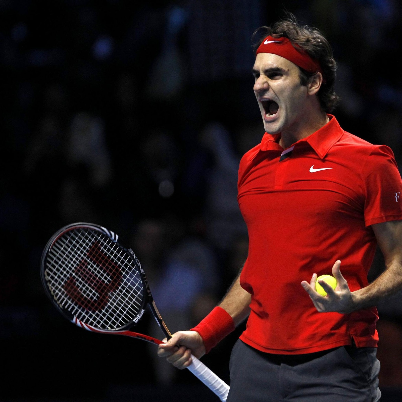 Un joueur de tennis avec un t-shirt rouge et un pantalon noir tenant une raquette de tennis (federer, roger, tennis)