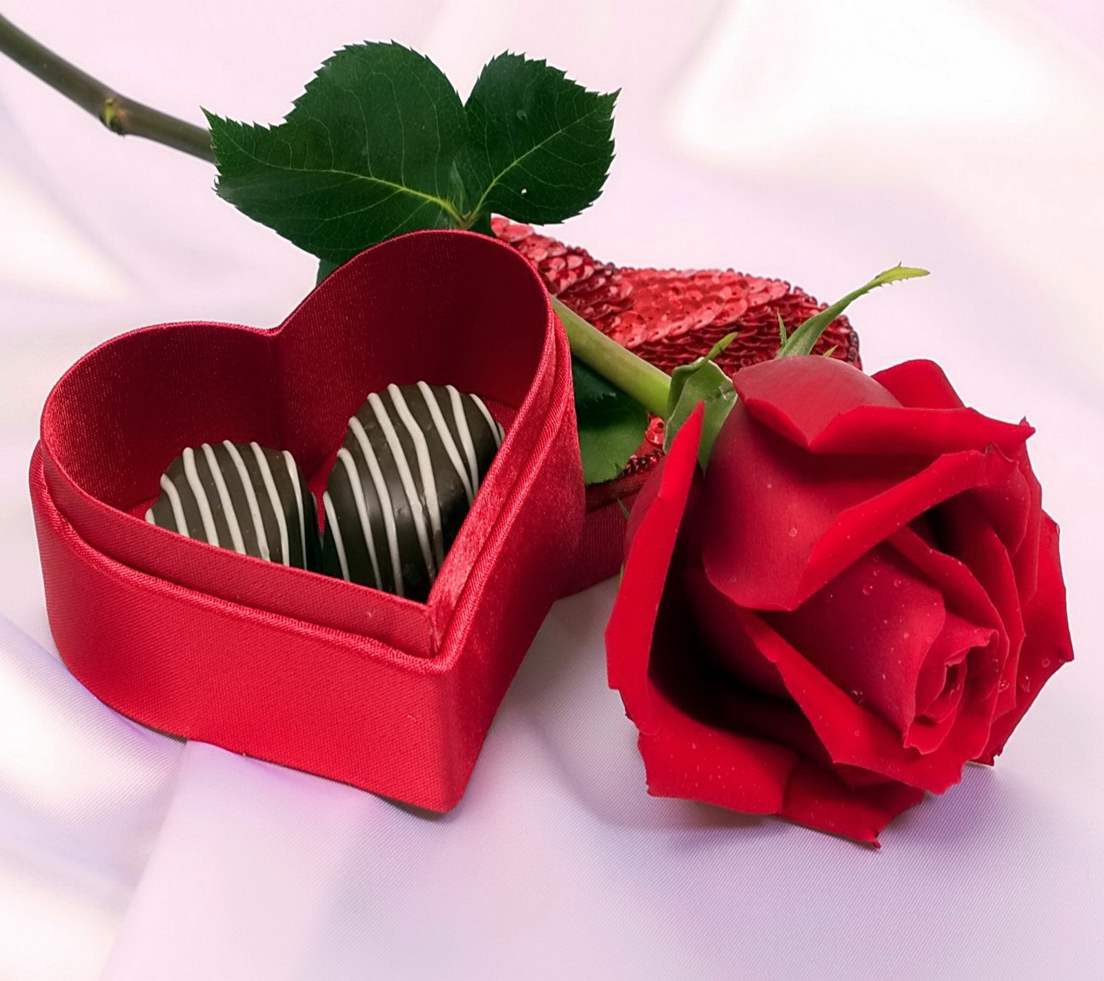 Il y a une rose rouge et une boîte en forme de cœur avec des chocolats (chocolat, cadeau, cœur, amour, romantique)