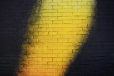 Illuminated Yellow Texture on Black Brick Wall