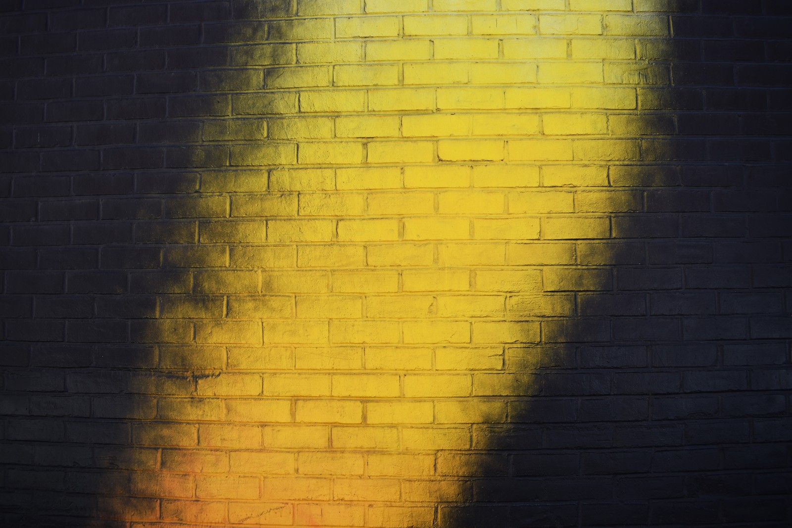 Image floue d'un hydrant jaune sur un mur en briques (lumière, jaune, noir, brique, ombre)