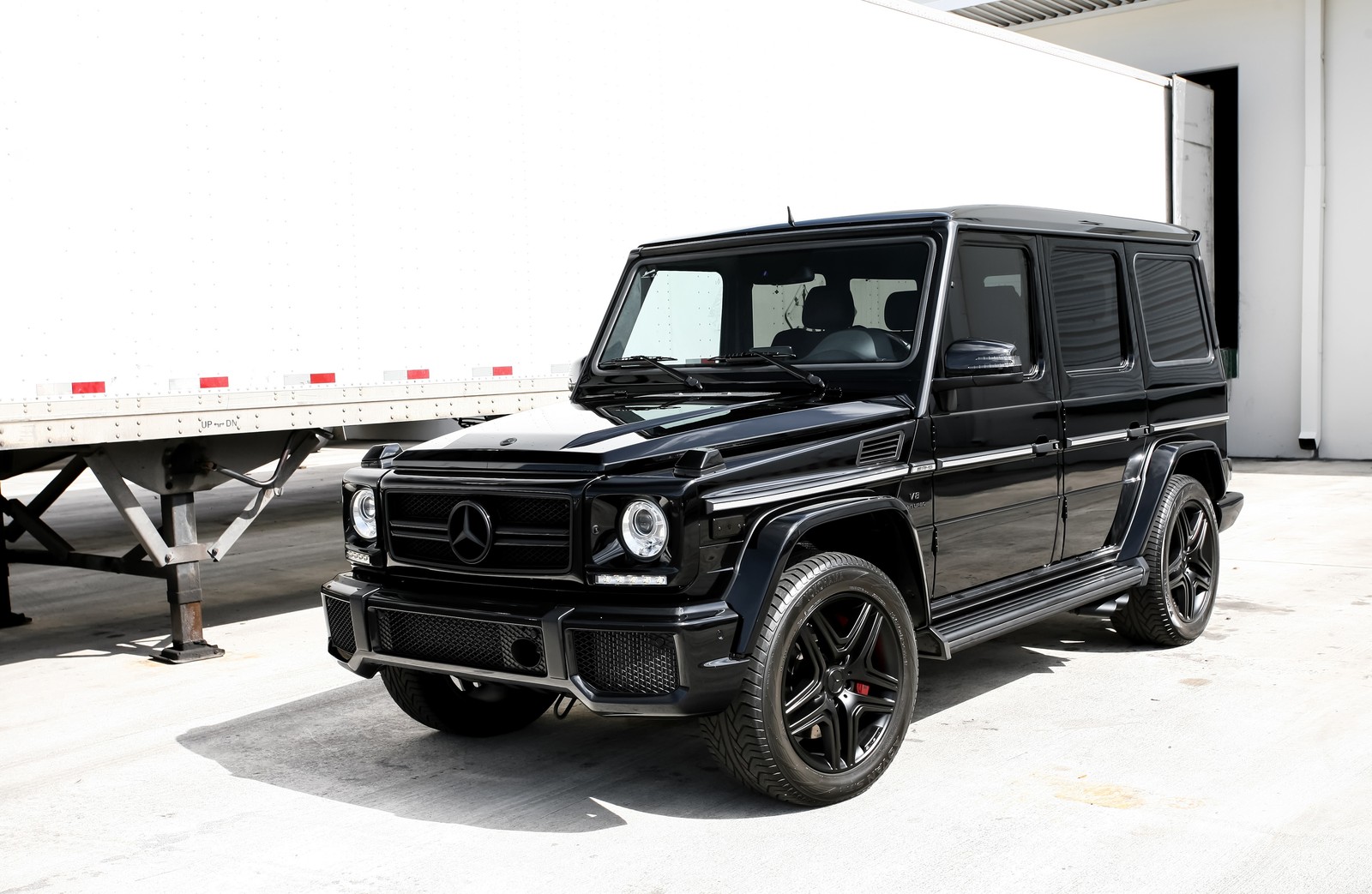 Une mercedes g-class noire garée devant un camion (voiture, réglage de voiture, pneu automobile, pneu, jante)