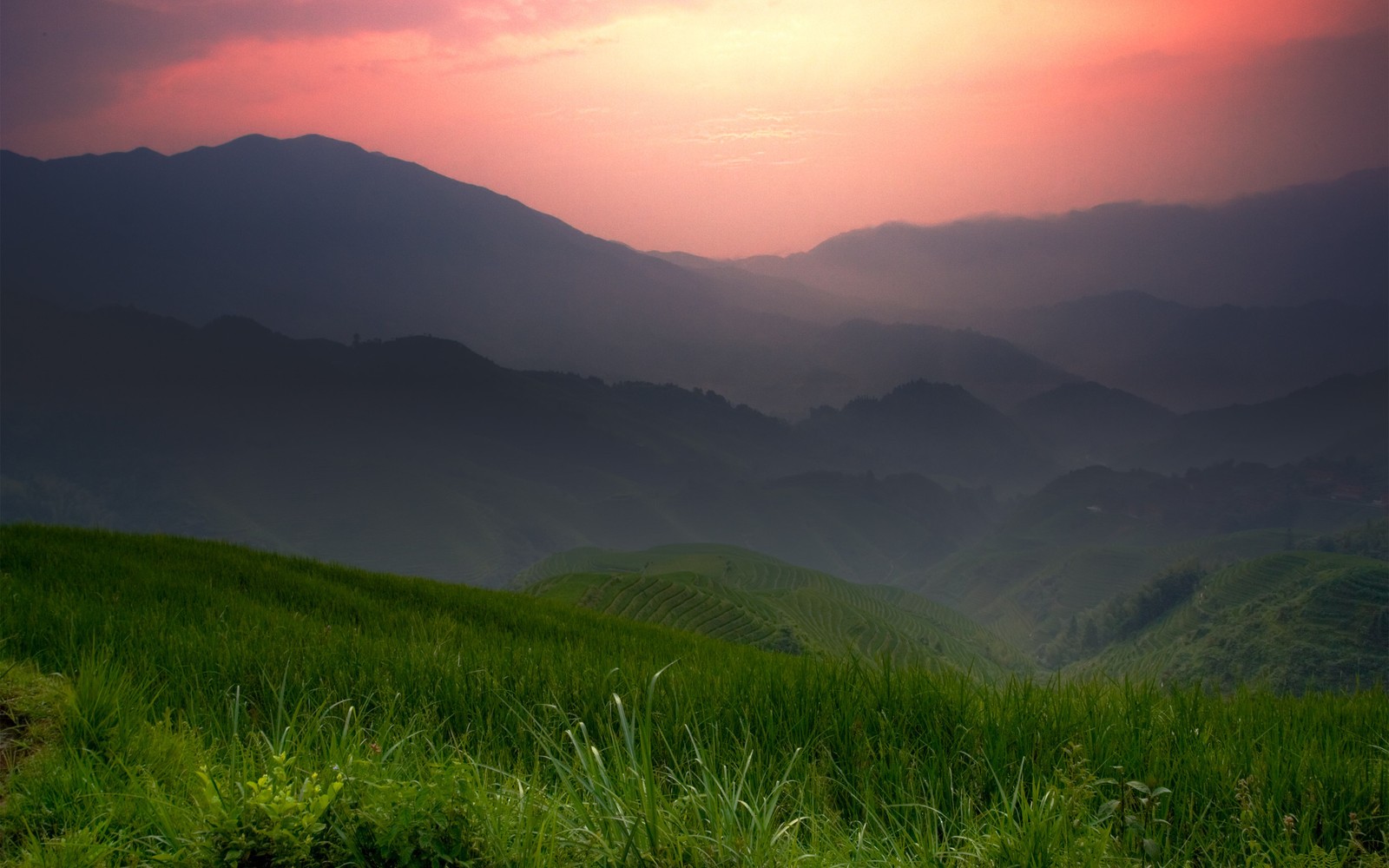 Arafed view of a mountain range with a sunset in the background (nature, highland, mountainous landforms, grassland, hill)