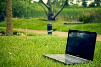 Netbook en hierba verde en medio de un paisaje natural