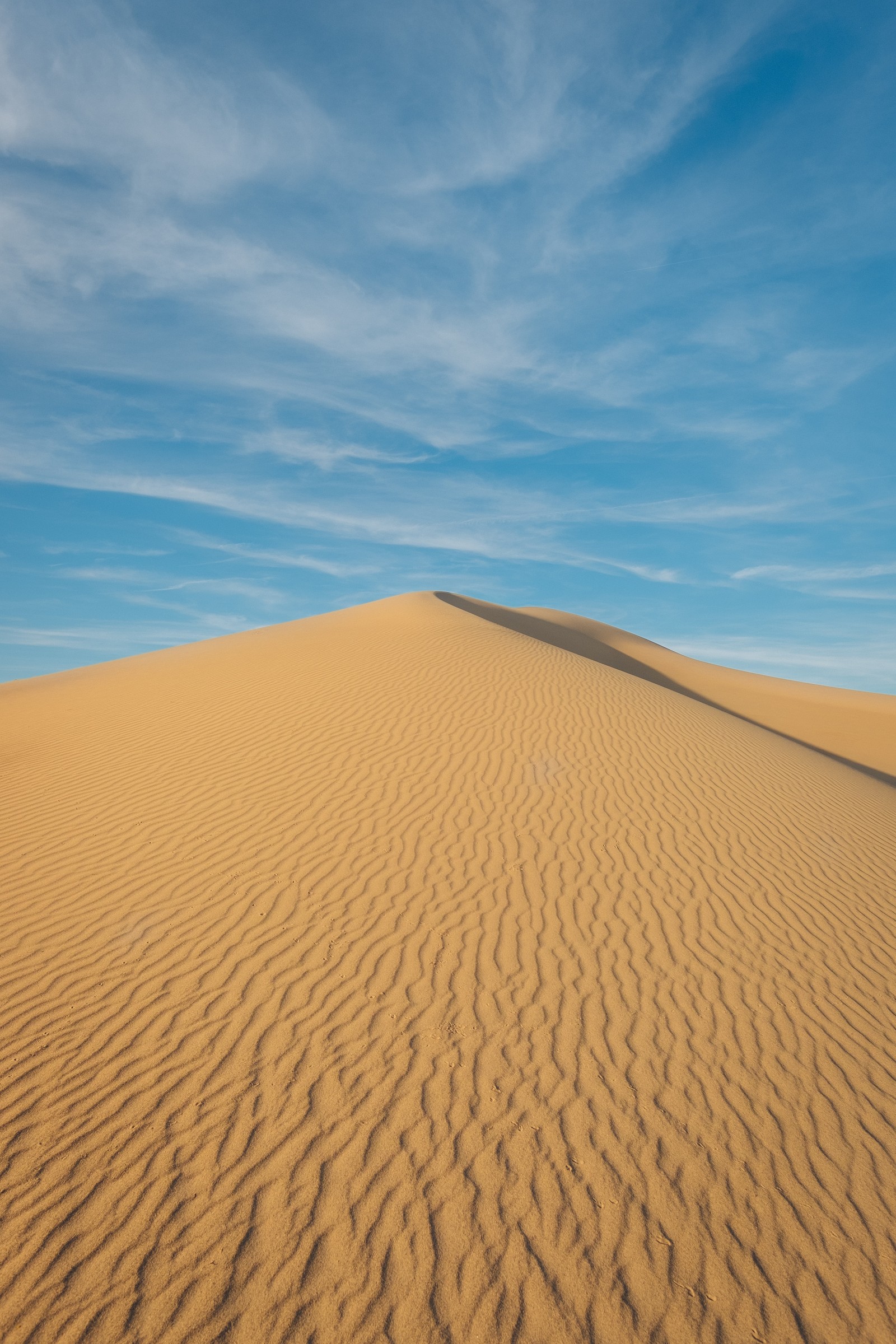 Uma duna de areia no deserto sob um céu azul (erg, areia cantante, duna, dune, areia)