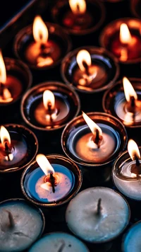 An array of lit candles and oil lamps casting warm light, symbolizing spirituality and prayer in diverse religious practices.