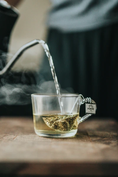 Thé vert fumant dans une tasse en verre avec un sachet de thé