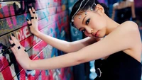 Jennie de BLACKPINK posando con estilo frente a una vibrante pared de graffiti.